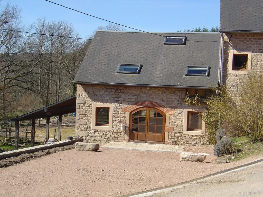 Bâtiment en pierre avec portes en bois cintré et velux sur toit ardoisé
