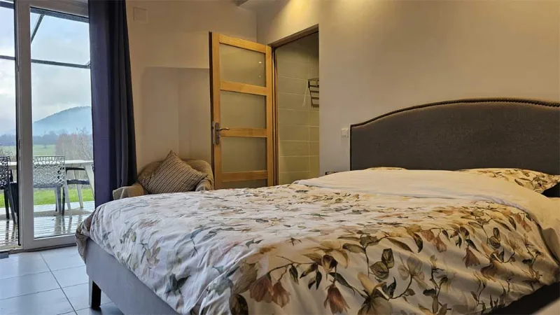Chambre double avec lit fleuri, baie vitrée ouvrant sur vue montagne