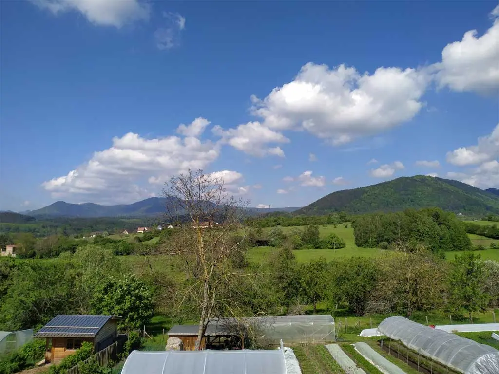Gîte de groupe Le Clos du Haslach à Niederhaslach — Vue panoramique sur collines alsaciennes avec potager et serres en contrebas, capacité 15 personnes
