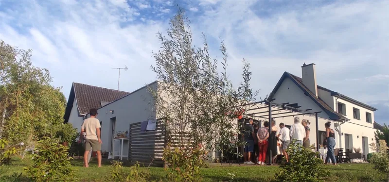 Maison moderne blanche avec groupe en terrasse sous olivier au coucher de soleil