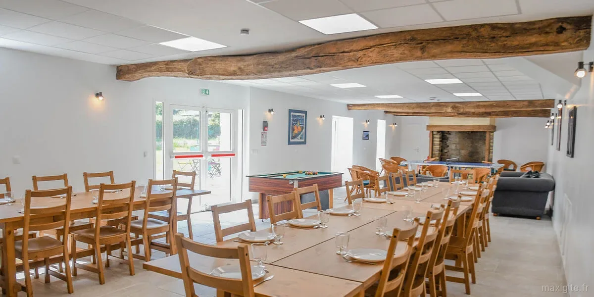 Gîte de groupe Gîte Entre Terre et Mer à Surzur — Grande salle de réception aux poutres apparentes, longues tables dressées, billard et cheminée en pierre, capacité 30 personnes