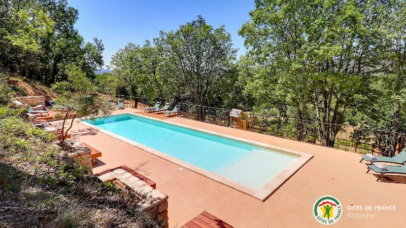Piscine sur terrasse ocre entouree de vegetation mediterraneenne avec transats et vue degagee