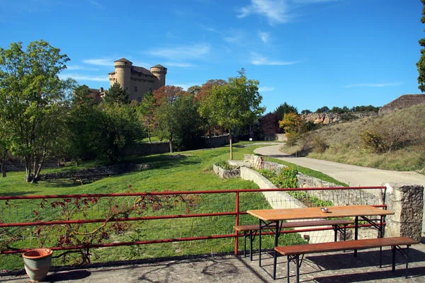 Jardin verdoyant et table de pique-nique avec vue sur un château médiéval sous ciel bleu