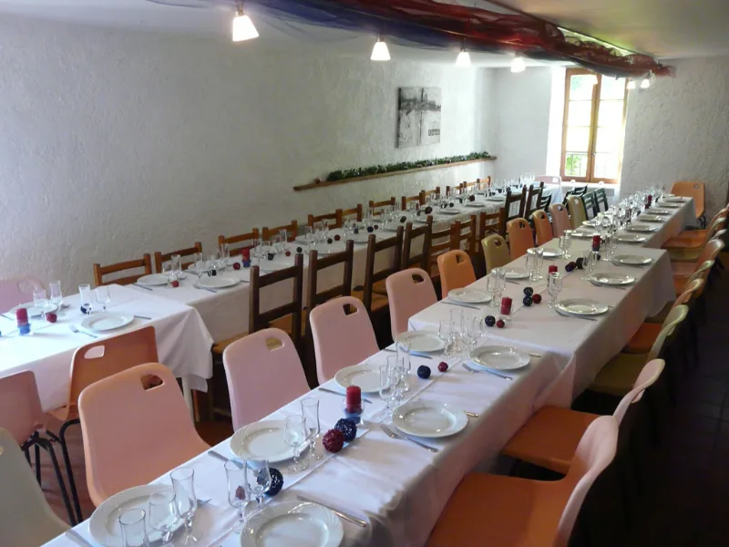Vaste salle de réception aux tables dressées et chaises colorées pour repas de groupe nombreux