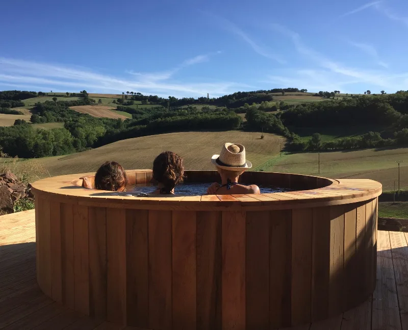 Sauna-tonneau en bois sur terrasse avec vue panoramique sur les collines aveyronnaises