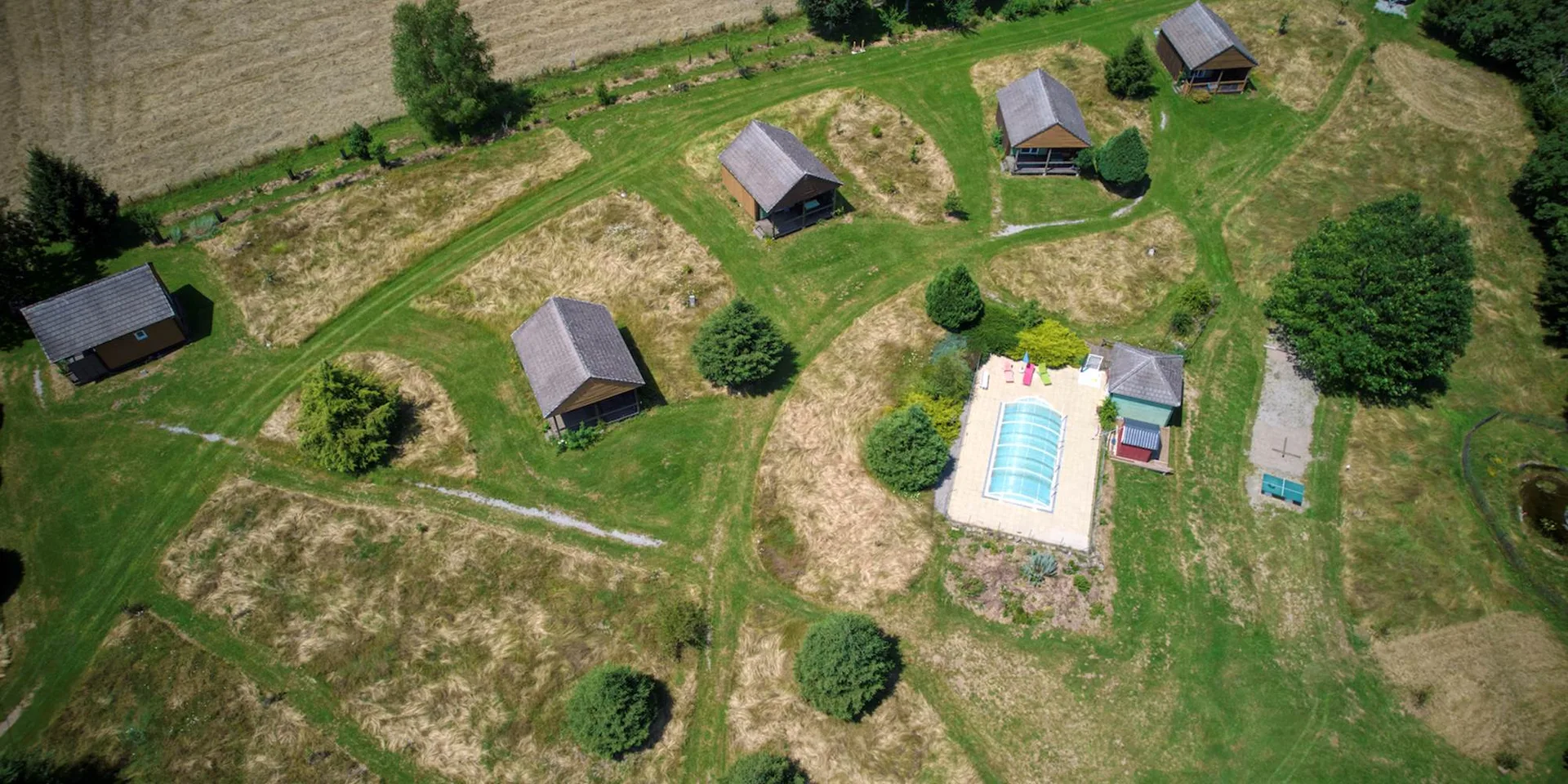 Gîte de groupe Les Maisons de Coline à Sérandon — Vue aérienne des Maisons de Coline avec ses chalets en bois au milieu des prairies et forêts, capacité 30 personnes