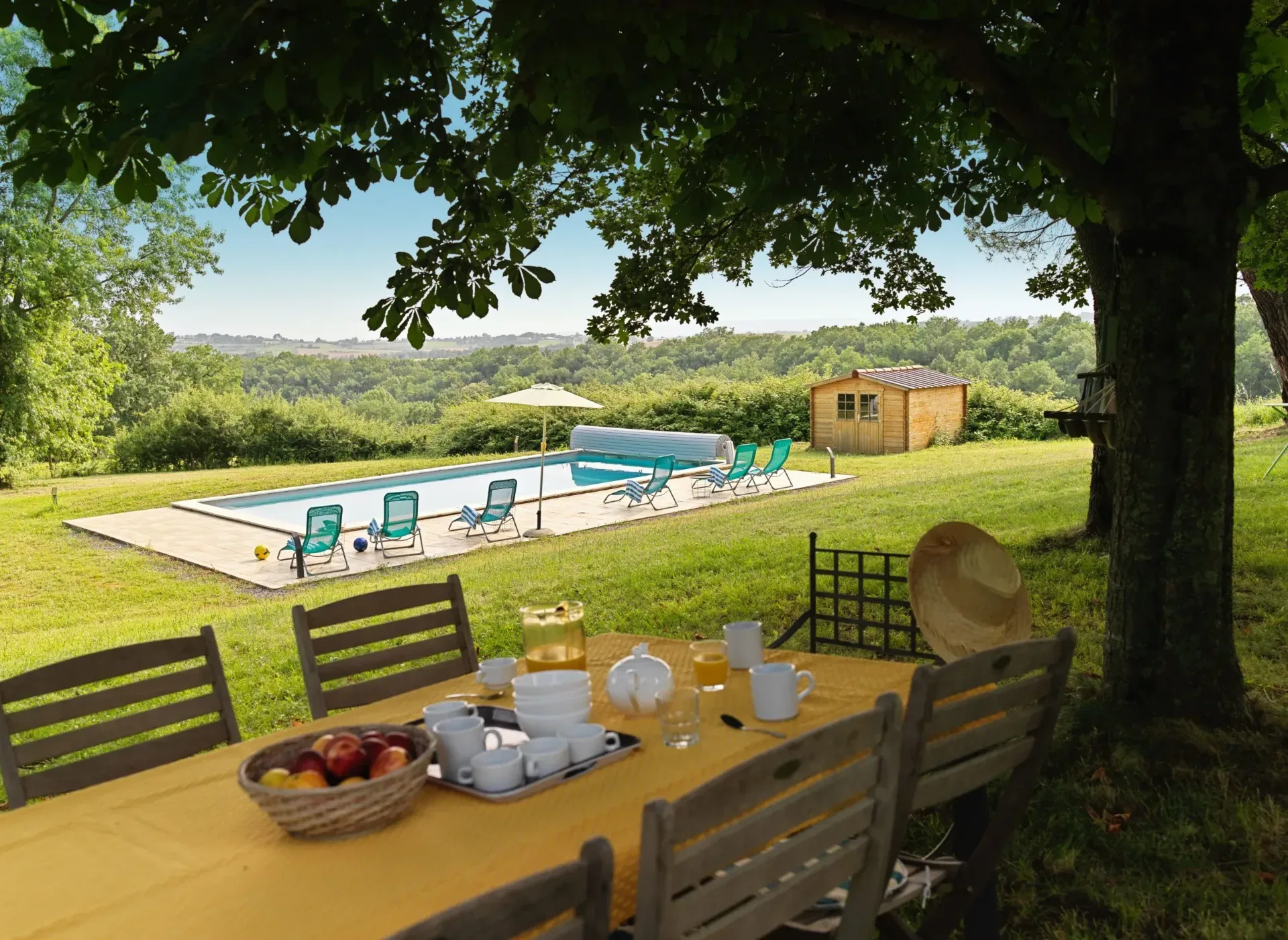 Gîte de groupe Domaine de La Planésié à Roquecourbe — Le parc et la piscine du domaine, table dressée à l'ombre des arbres, capacité 18 personnes