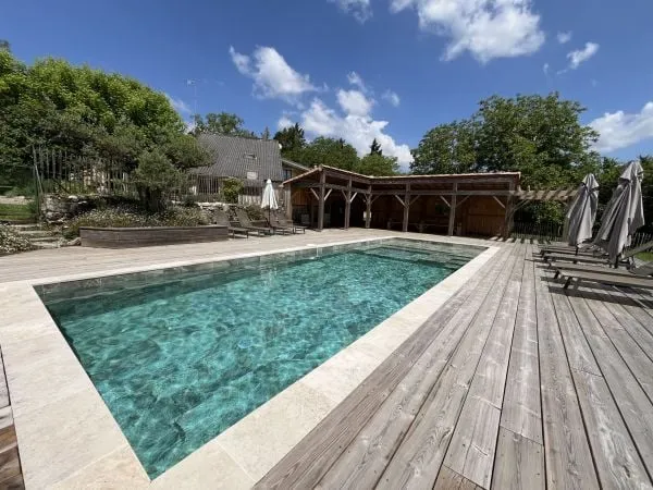 La piscine extérieure du domaine entourée de rosiers et de transats