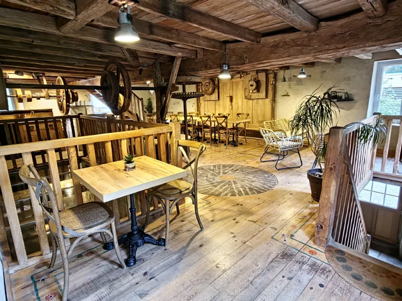 Salle à manger de moulin avec parquet, tables en bois et galerie mezzanine