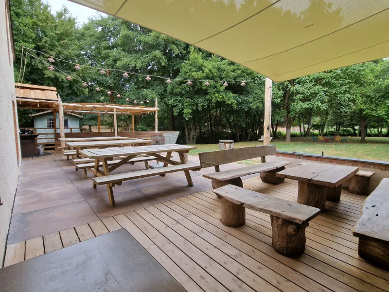 Grande terrasse en bois sous voile d'ombrage avec tables pique-nique