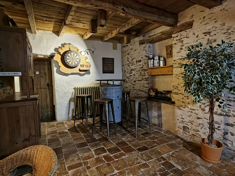 Bar rustique avec cible de fléchettes, tabourets hauts et mur en pierre