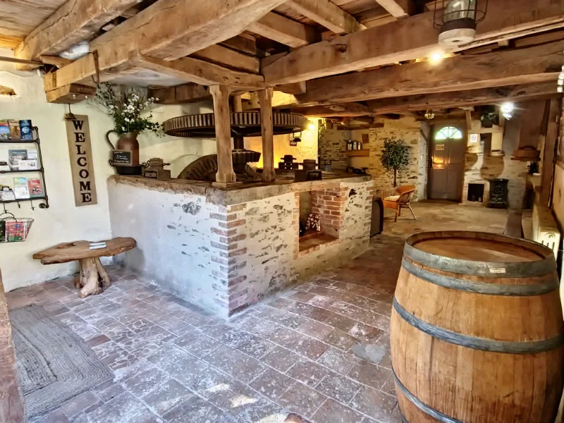 Hall de moulin avec poutres en bois, tonneau, four en briques et dallage ancien
