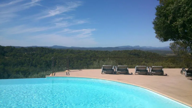 Piscine à débordement avec transats et vue panoramique sur garrigues provençales