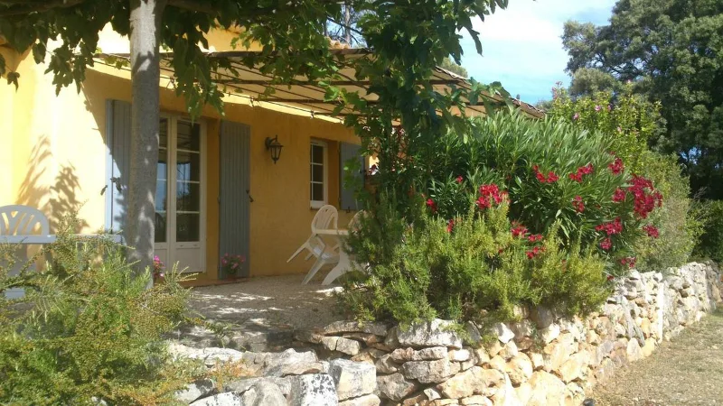 Bastide provençale jaune avec jardin fleuri et muret en pierre sèche