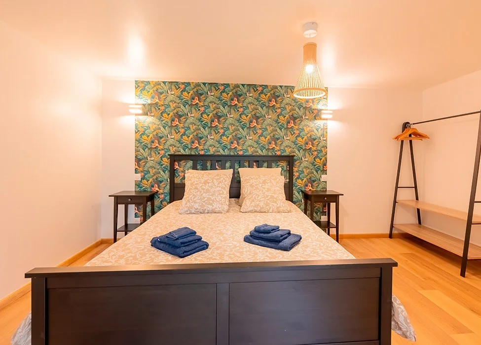 Chambre avec lit double, tête de lit fleurie et dressing ouvert