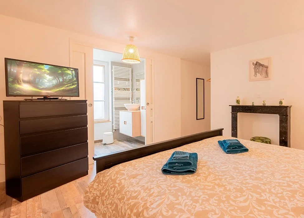 Chambre avec lit double et têtes de lit capitonnées sous poutres
