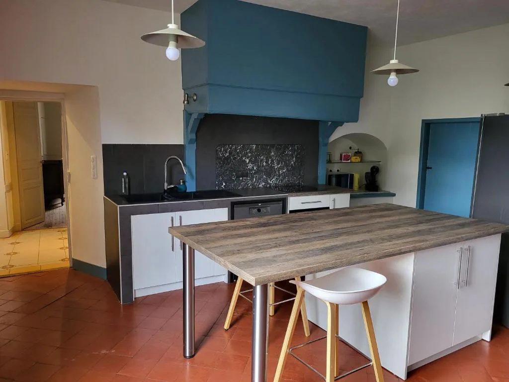 Cuisine équipée avec îlot central bleu et coin repas convivial