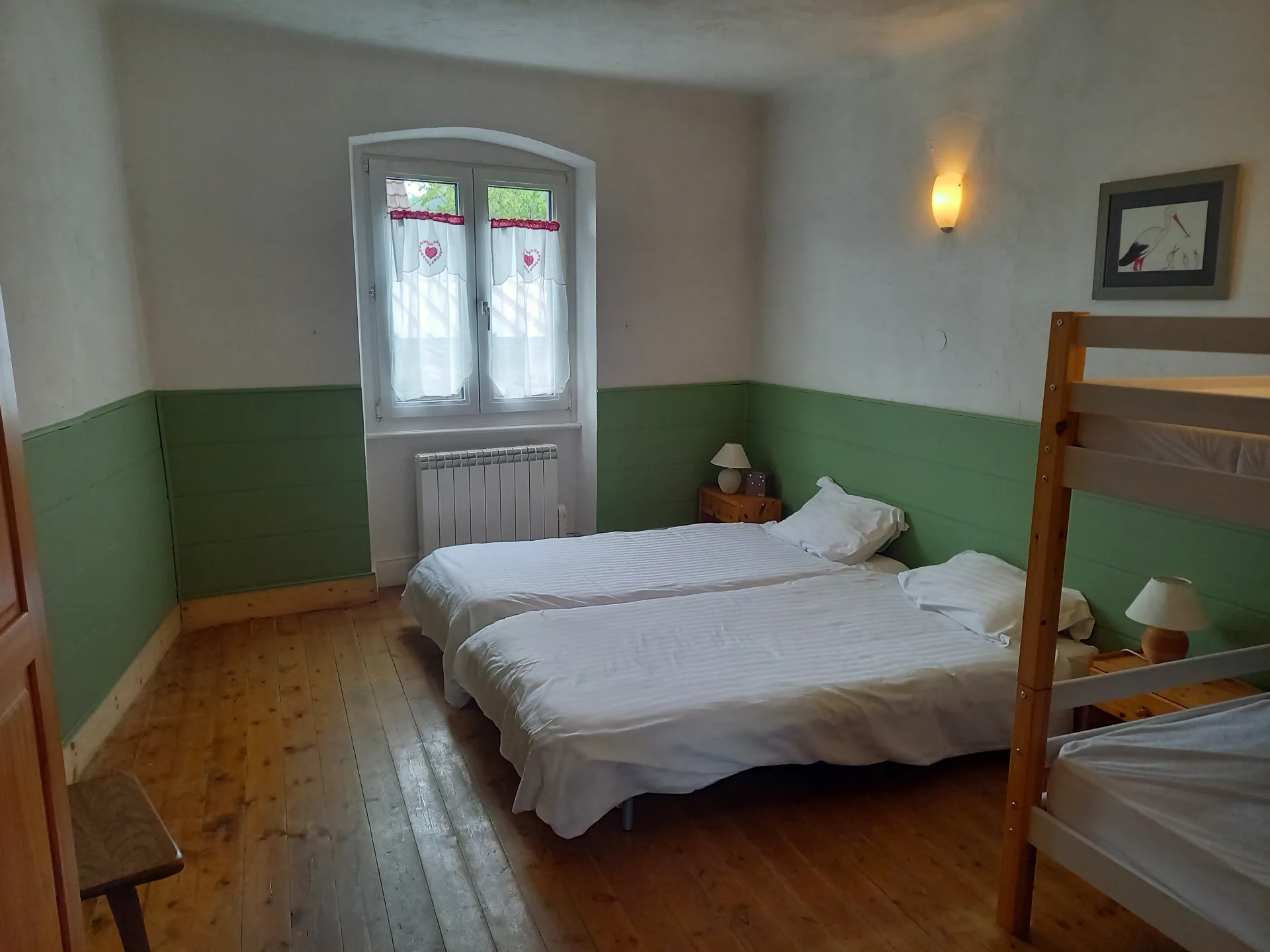 Chambre aux murs vert sauge avec deux lits jumeaux et lit superposé en bois