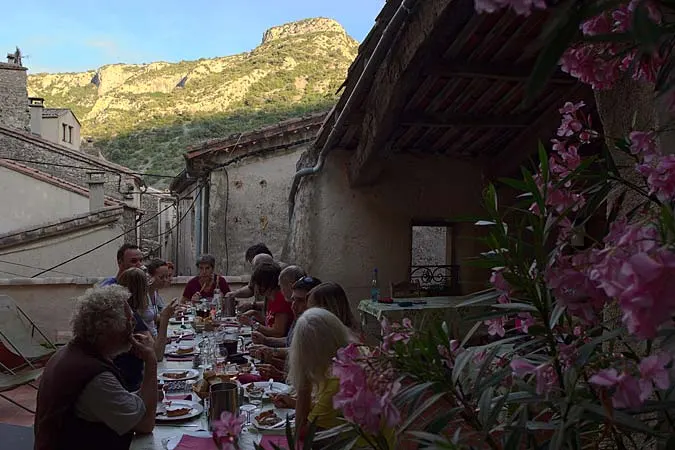 Repas de groupe en terrasse avec vue sur falaises calcaires au coucher du soleil