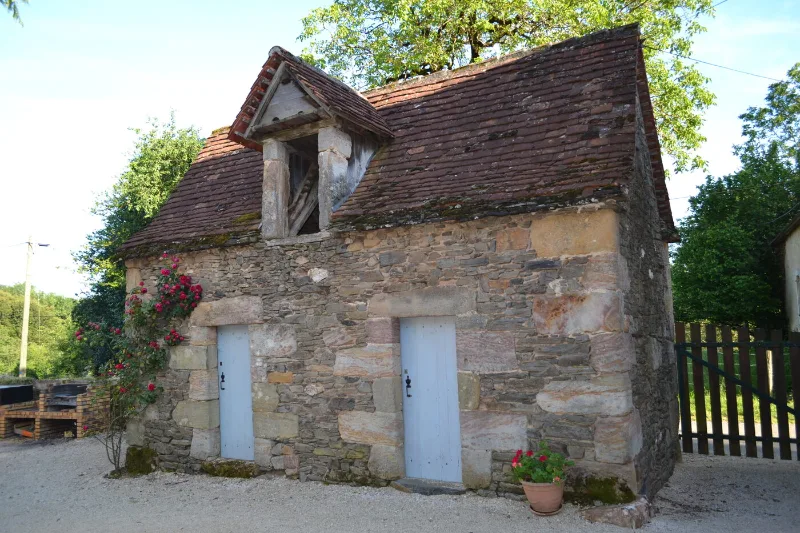Ancienne grange en pierre du Quercy avec toiture en tuiles et rosier grimpant
