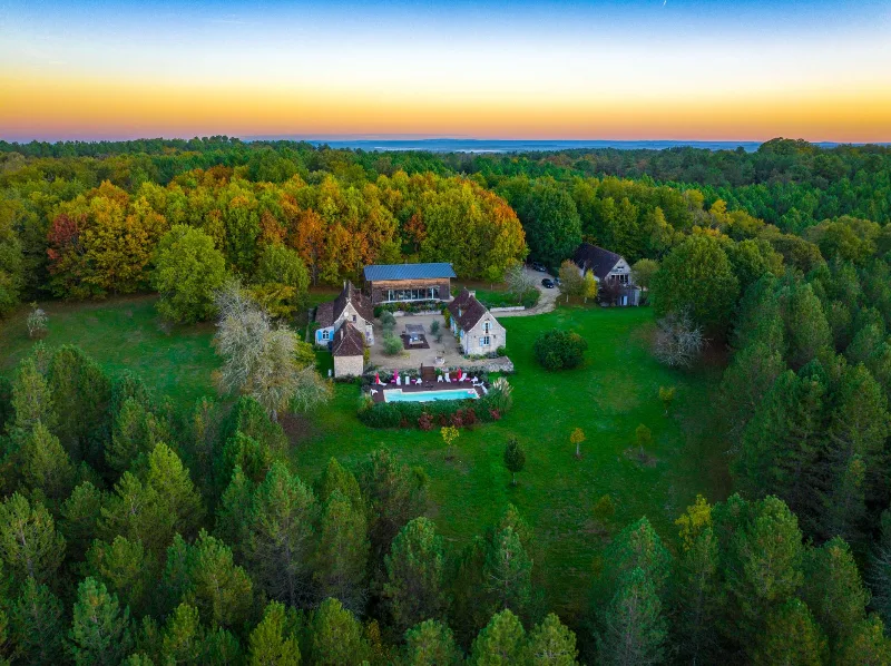 Vue aérienne du domaine en Périgord avec bâtisses en pierre, piscine et forêt environnante