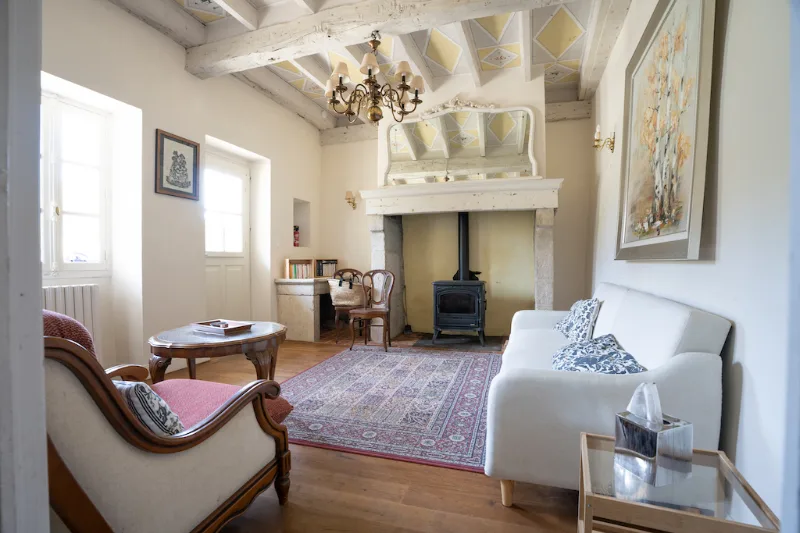 Second salon cosy avec poêle à bois, fauteuils anciens et tapis persan