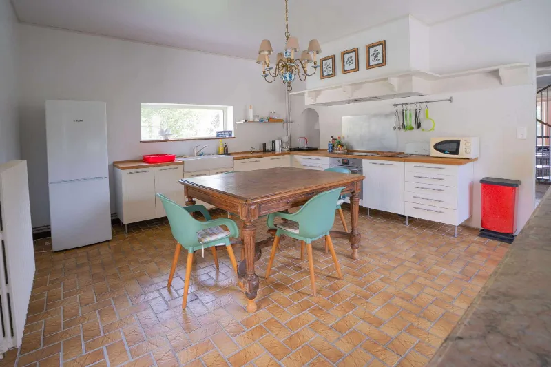Cuisine équipée moderne avec grande table en bois et chaises vertes