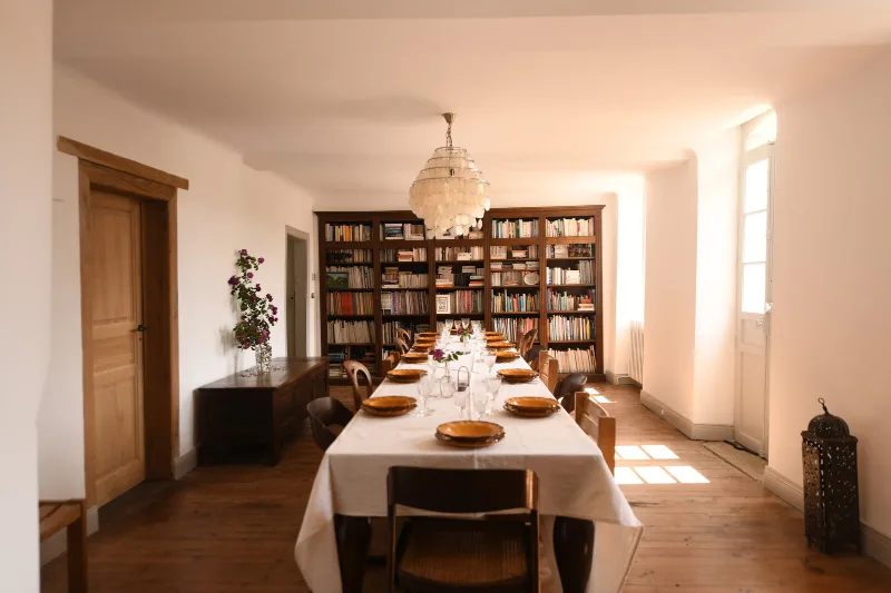 Salle à manger raffinée avec table dressée devant une bibliothèque en bois