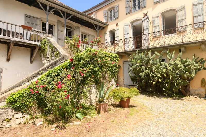 Cour intérieure en pierre bordée de rosiers grimpants et d'un escalier extérieur