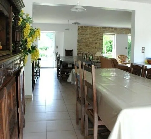 Salle à manger avec longue table dressée pour un grand groupe et mur en pierre au fond