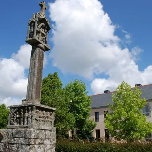 Gîte de groupe Enterdeuz-Golfe du Morbihan à Saint Nolff — Calvaire en granit devant la longère bretonne, entouré d'arbres et de verdure, capacité 24 personnes