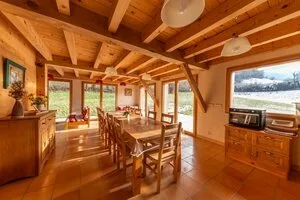 Salle à manger chaleureuse avec charpente apparente et grande table en bois massif