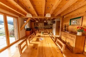Cuisine et salle à manger en bois avec longue table dressée pour un groupe, vue sur la campagne