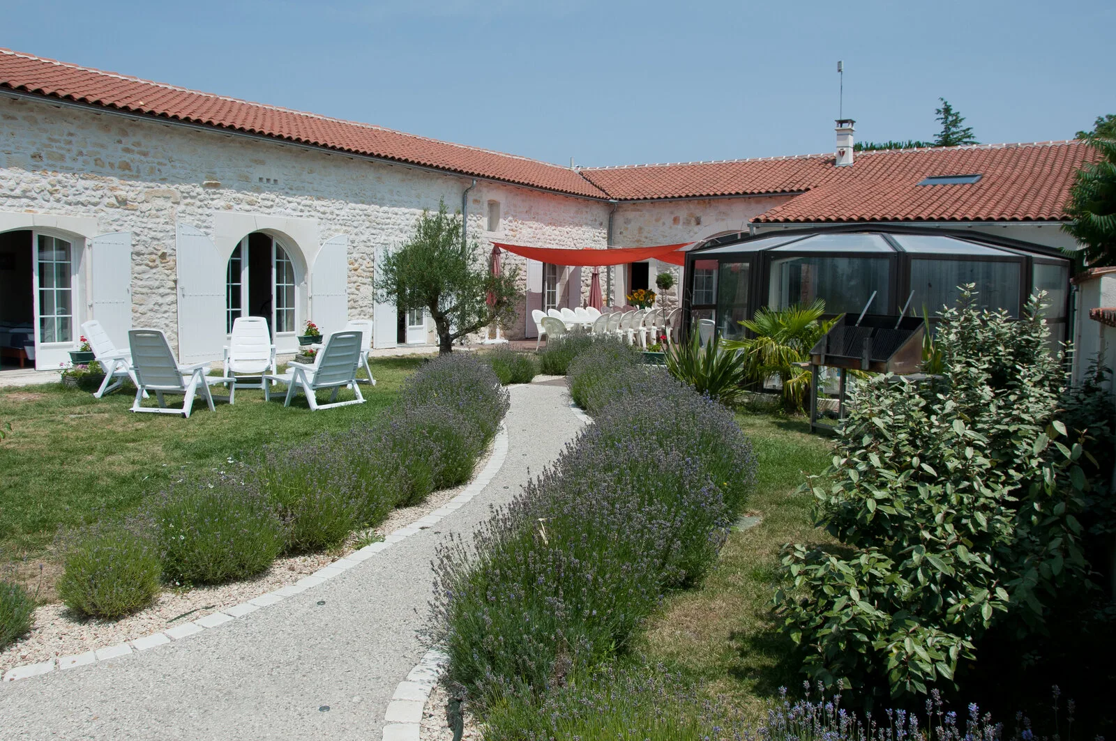 Gîte de groupe La Grande Champagne à Rioux — Façade en pierre de l'ancienne ferme charentaise avec jardin de lavande et véranda vitrée, capacité 26 personnes