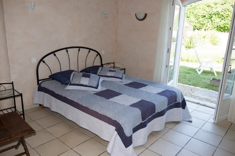 Chambre double avec tête de lit en fer forgé et accès direct au jardin