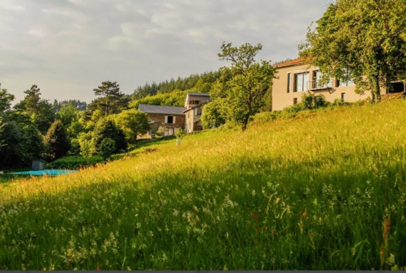 Vue d'ensemble du domaine en pleine nature avec piscine et bâtiments en pierre entre les arbres