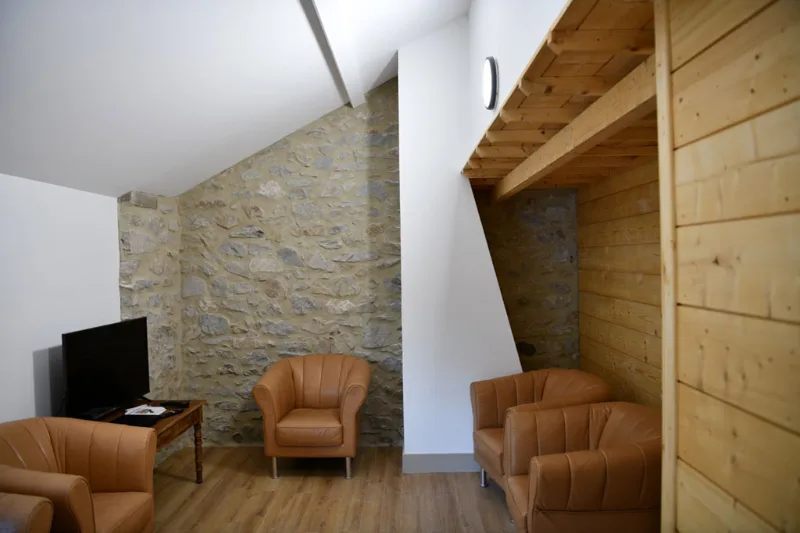 Coin salon avec fauteuils en cuir contre un mur en pierre ancienne