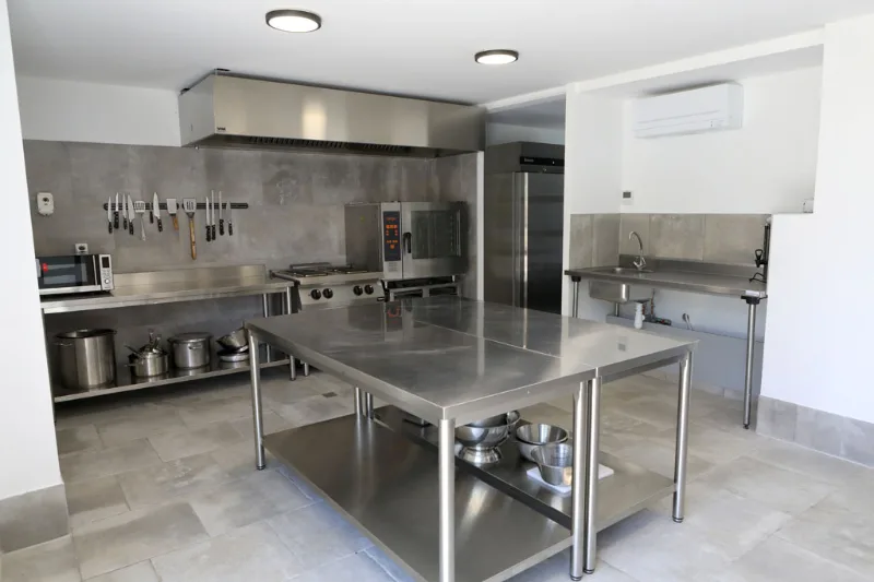 Cuisine professionnelle équipée avec inox et vaste plan de travail pour groupes