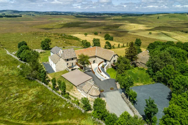 Gîte de groupe Domaine du Barena - Au Coin du Feu à Prinsuejols-Malbouzon — Vue aérienne du domaine en pierre au cœur des plateaux de l'Aubrac, capacité 12 personnes