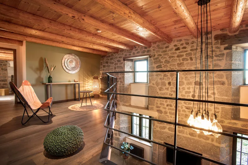 Mezzanine ouverte avec charpente en bois et murs en pierre du pays