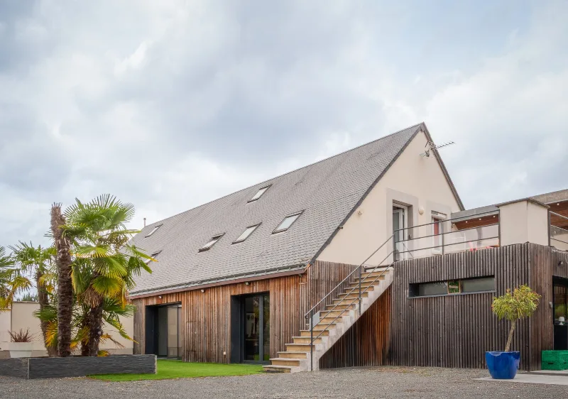 Maison contemporaine à toit d'ardoise avec bardage bois et grand escalier extérieur