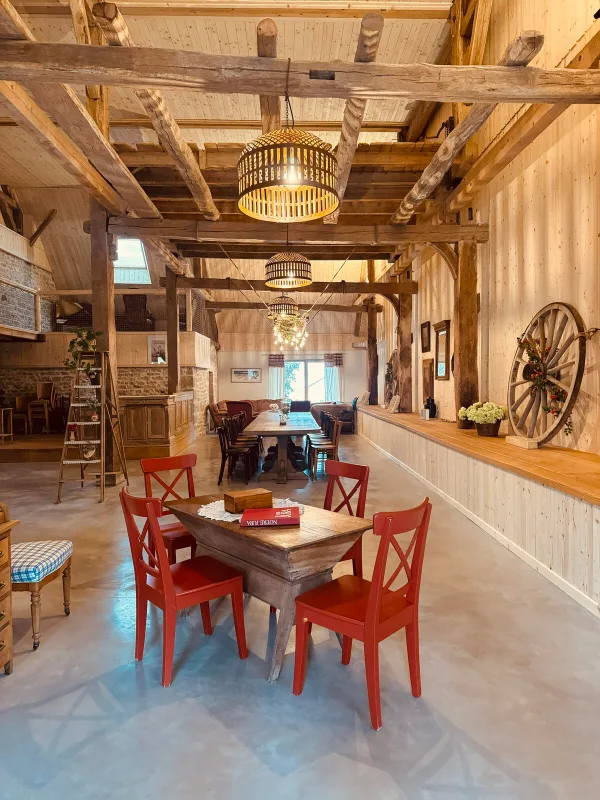 Table dressée dans la grange avec chaises rouges et échelle décorative pour les repas de groupe