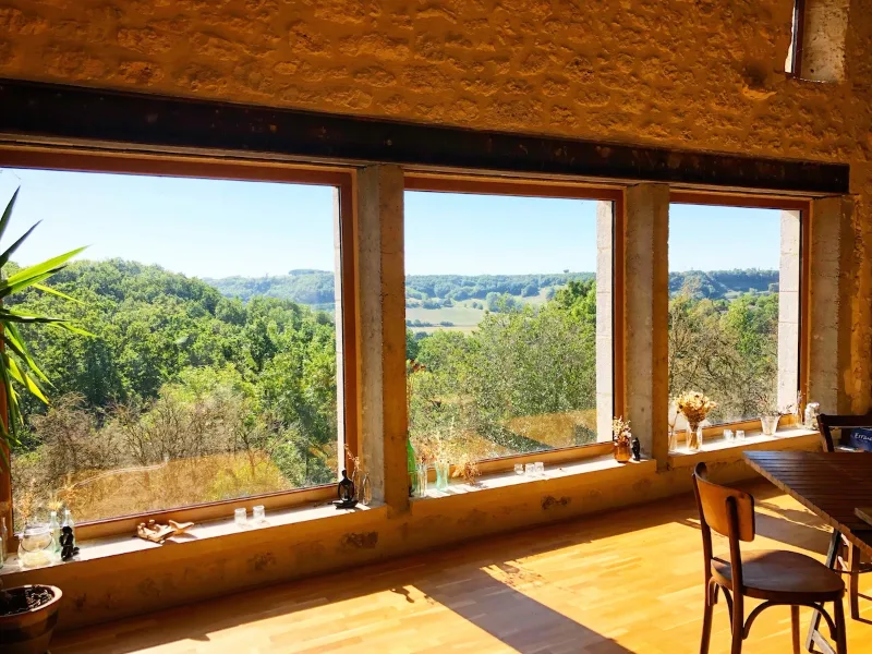 Salle à manger de la grange avec grande table en bois sous charpente traditionnelle
