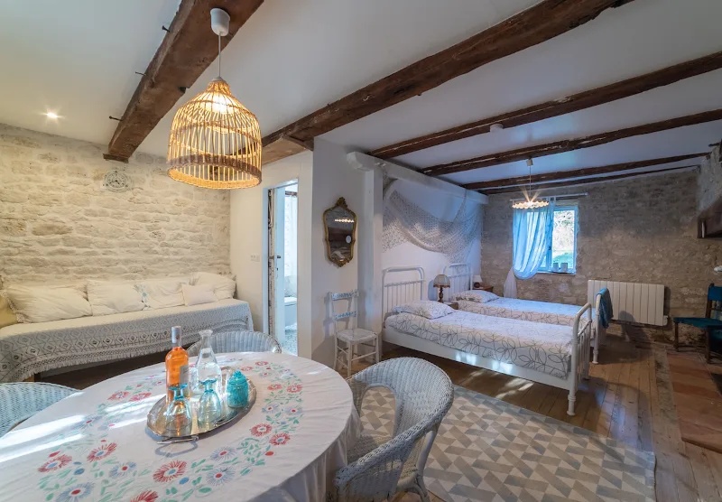 Chambre lumineuse avec deux lits, mezzanine et pierres apparentes