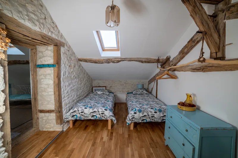 Chambre cosy avec linge de lit fleuri et poutres en bois