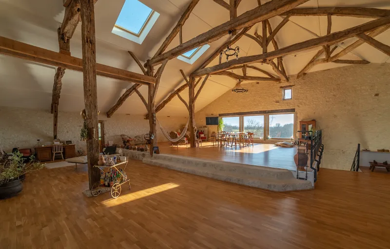 Salon dans la grange rénovée avec charpente apparente et mezzanine