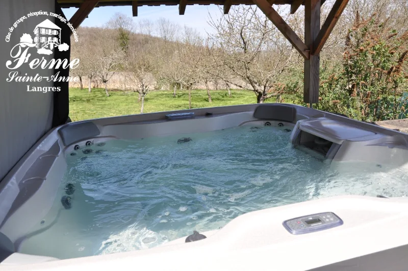 Jacuzzi extérieur couvert entouré d'un verger, vue dégagée sur la campagne