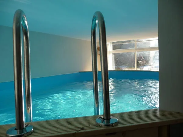 Piscine intérieure chauffée avec échelle métallique et grandes fenêtres