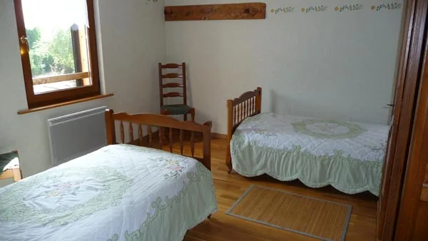Chambre avec deux lits simples et parquet en bois