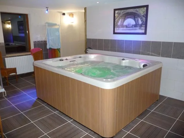 Spa jacuzzi intérieur avec éclairage tamisé et carrelage foncé